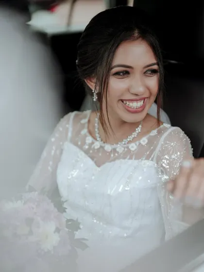 A candid shot of a Christian bride's joyful smile as she sits in the car, ready for her wedding.