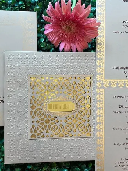 A full view of our white and gold invitation set, featuring a laser-cut 'jaali' window. The set includes multiple inserts for all wedding events, including a QR code for directions.