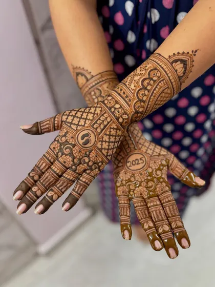 A baby shower mehendi design with a tiny baby footprint in the center of the palm and the year "2025".