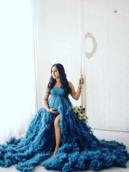 A stunning portrait of a mother-to-be in a deep blue gown, seated on a swing. This shot has a beautiful, almost painting-like quality.