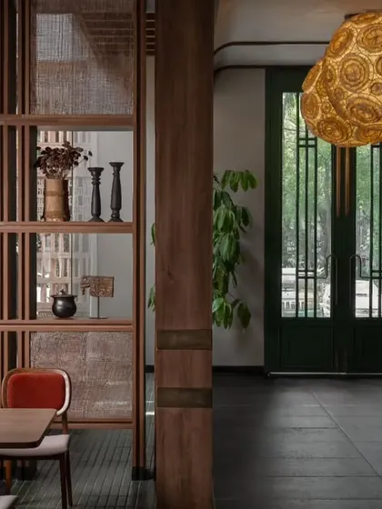 A detail shot focusing on the custom wooden partitions with cane webbing. These elements help to create intimate dining zones while allowing light and air to flow through the space, adding to the restaurant's open feel.