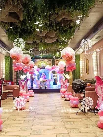 The entire venue is transformed into a butterfly garden with themed balloon pillars and hanging decor, creating an immersive experience from the moment guests walk in.