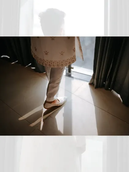 An artistic shot focusing on the groom's feet and the beautiful shadows cast by the morning light as he gets ready for his wedding.