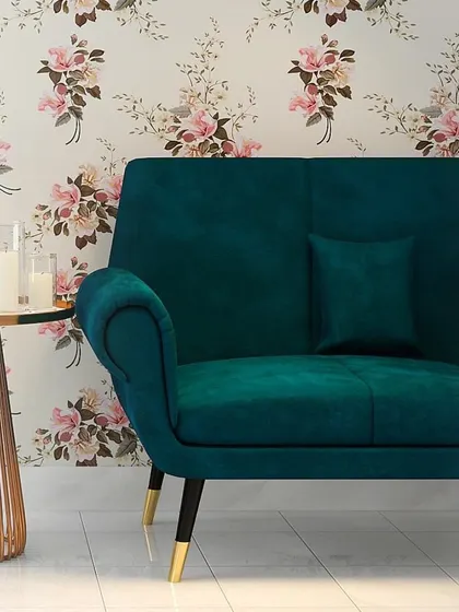 A close-up of a vibrant teal armchair against a floral wallpaper, demonstrating how we use bold colors and patterns to create unique, personality-filled spaces.