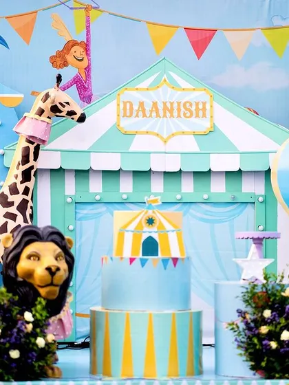 A detailed view of the pastel carnival cake table. The design features a circus tent backdrop, a friendly lion, and a tall giraffe, all in a unique and soft color palette.