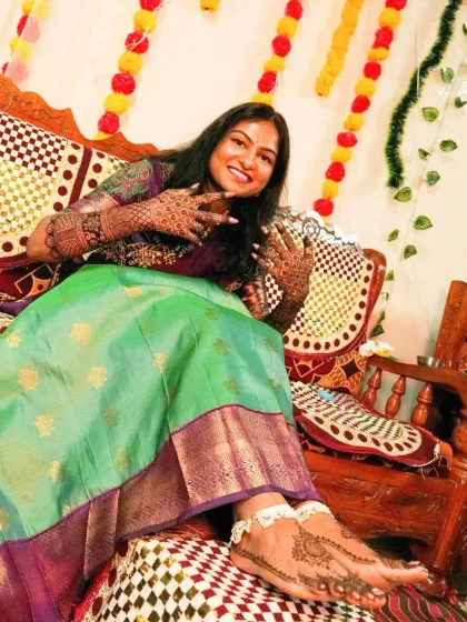 A candid shot of a happy bride, with her beautiful hand and feet mehendi on full display.