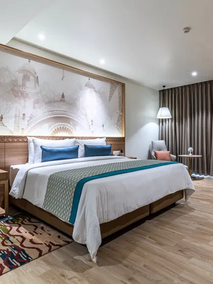 A guest room at Hotel Sarovar Portico, where the wallpaper is inspired by Junagadh’s heritage architecture. This contextual element brings the region's unique history and style directly into the guest's private space.