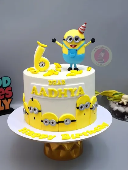 A fun Minion-themed cake for Aadhya's 6th birthday, with a happy Minion on top and little Minions peeking around the base.