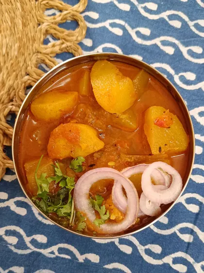 A bowl of my Aloo Lauki ki Sabzi, garnished with fresh onion rings. The potatoes and bottle gourd are cooked until tender in a light, tomato-based gravy.