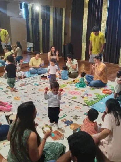 A little one takes center stage with egg shakers while the group supports him. This shows how my classes help build confidence and social skills in a group setting.