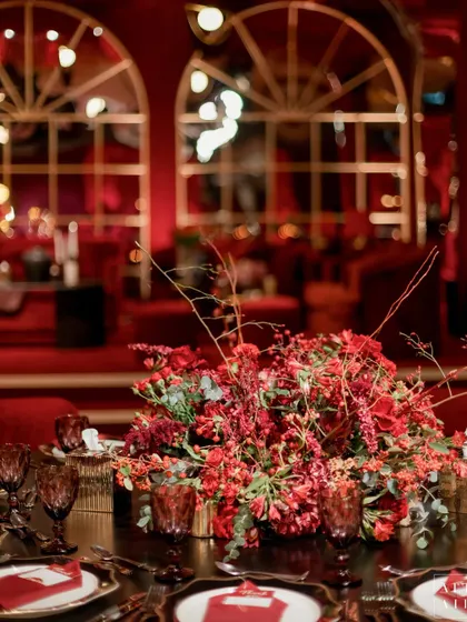 A close-up of a floral arrangement at 'Le Rouge'. The deep red flowers and dark foliage perfectly matched the dramatic and moody aesthetic of the burlesque-themed sangeet.