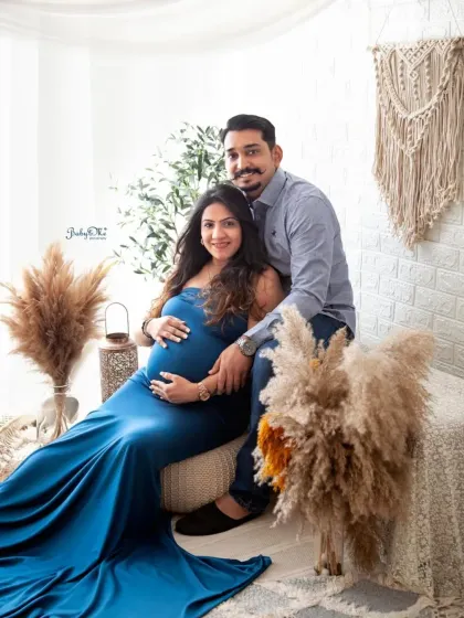 This expecting mother looks like a queen in a beautiful blue gown. The boho setup adds a touch of earthy elegance to her maternity portrait.