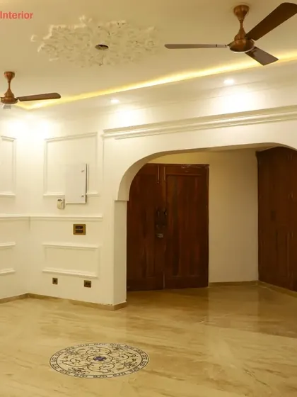An elegant living space featuring classic wall molding, a graceful archway, and a decorative marble inlay on the floor.
