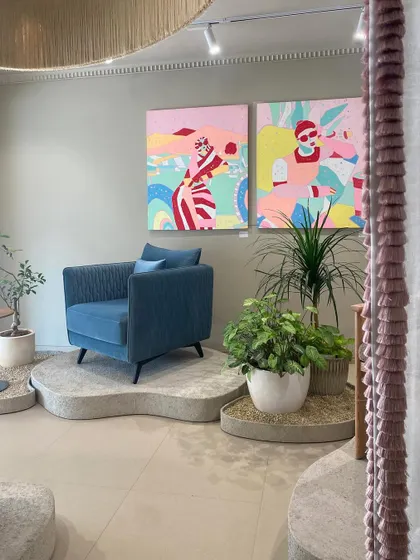 Art is integral to the space, not an afterthought. Vibrant, contemporary paintings are paired with a bold blue armchair on a custom concrete plinth, creating a striking focal point that blurs the line between a furniture store and an art gallery.