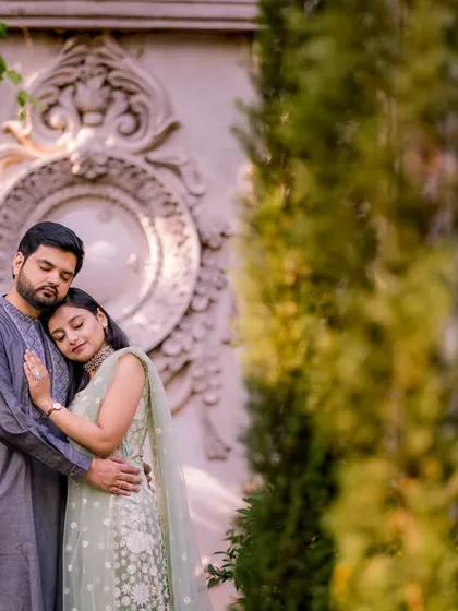 A quiet, intimate moment in a lush green setting. The natural framing and the couple's gentle embrace make this a very romantic portrait.