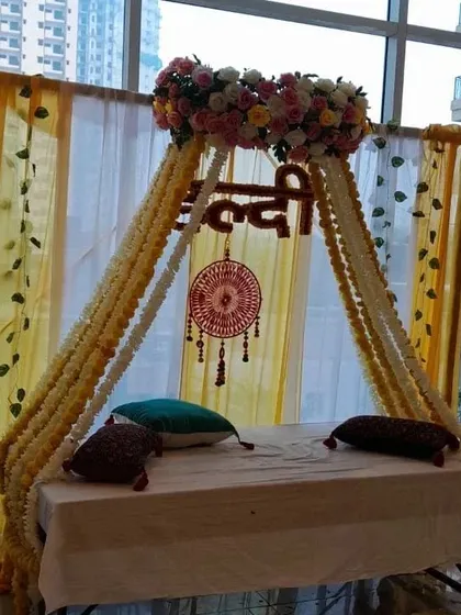 A swing-style seating arrangement for a Haldi ceremony, decorated with floral strings and a dreamcatcher. This setup is ideal for apartment balconies or smaller indoor spaces.