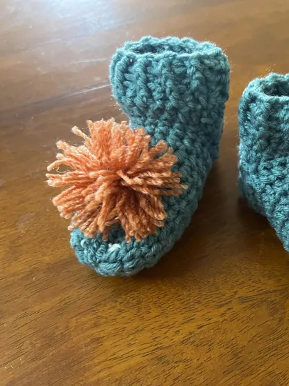 A close-up of the pom-pom baby bootie. The big, fluffy pom-pom is so playful and fun. It's securely attached so it's safe for babies.