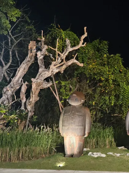 Even at night, the right sculpture can make an impact. This illuminated stone figure stands guard in a garden, showcasing how art can be integrated with landscape lighting.