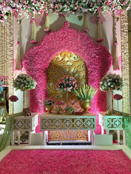 A stunning photo-op corner featuring a floral arch against a gold-patterned backdrop. The floor is a carpet of fresh pink petals, creating a truly immersive experience.