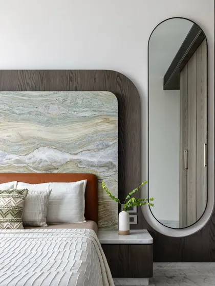 We love layering textures to create warmth and depth. This bedroom features a headboard combining a dramatic stone slab with a dark wood frame and a soft leather base, creating a rich tactile experience.