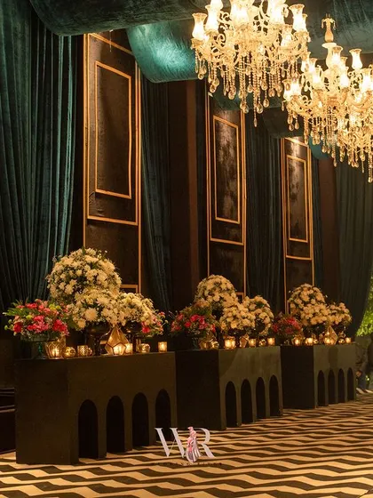 The full view of the grand entrance corridor, with its striking chevron floor, teal velvet drapes, and consoles overflowing with flowers, creating a truly immersive experience for arriving guests.