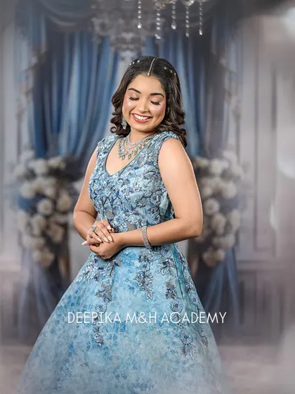 The model looking down, showcasing the soft curls in her hair and the intricate floral details on her blue gown.