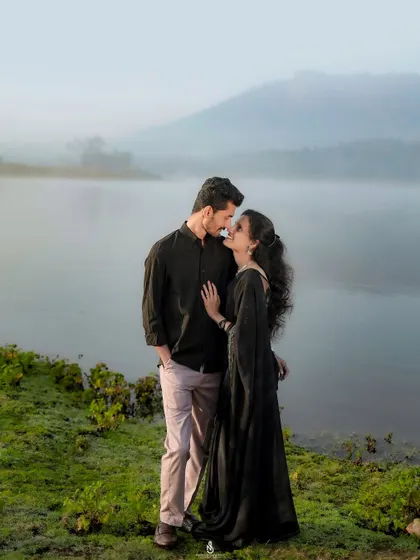 A gentle kiss shared at the water's edge, with the rolling hills of Karnataka faint in the misty background. A classic romantic shot for any couple's album.