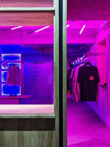A look through the entrance window, with the interior bathed in a futuristic pink and blue glow.