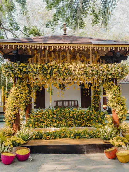 A Haldi mandap drenched in sunshine and yellow blooms. We use a monochromatic color scheme with various flowers like sunflowers and chrysanthemums to create a visually stunning effect.