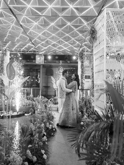 A timeless black and white portrait of the couple at their Mehendi. The custom-built structures, floral arrangements, and sparklers come together to create a truly magical and cinematic moment.