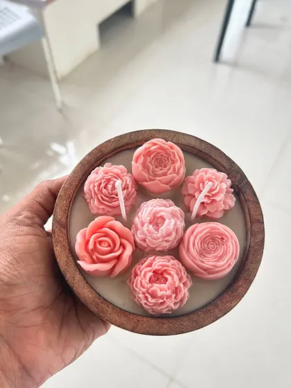 A beautiful wooden bowl filled with delicate pink peony and rose-shaped candles.