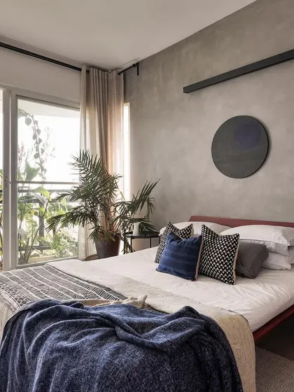 The 'Rustic Minimal' bedroom opens to a leafy balcony, a key feature of our design. We prioritize connecting interior spaces with outdoor greenery to enhance well-being and create a feeling of spaciousness.