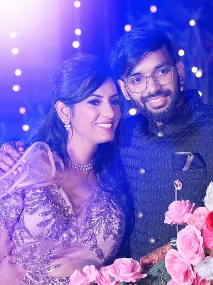 A joyful couple portrait from a wedding reception, with bright lights creating a festive atmosphere.