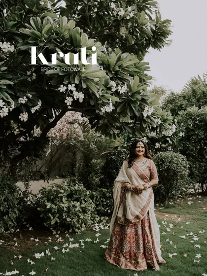 A portrait of the bride, Krati, standing gracefully amidst nature. The falling white flowers and lush greenery create a serene and beautiful backdrop for this timeless shot.