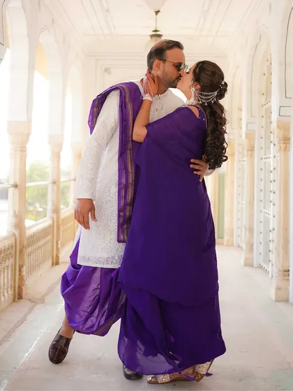 A romantic kiss in a beautiful palace corridor, the couple's deep purple outfits creating a rich and royal color palette.
