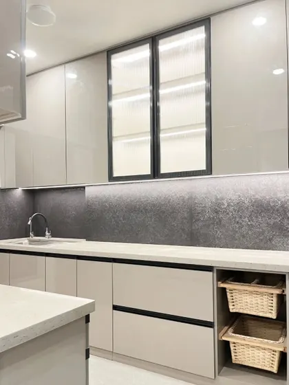 This view highlights the sleek, modern aesthetic of the grey kitchen, with its handleless design and textured black backsplash.