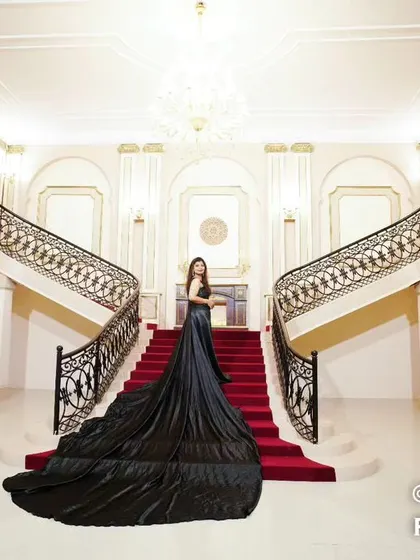 A stunning solo portrait of the bride-to-be on a grand staircase, her black trail gown cascading down the red-carpeted steps.