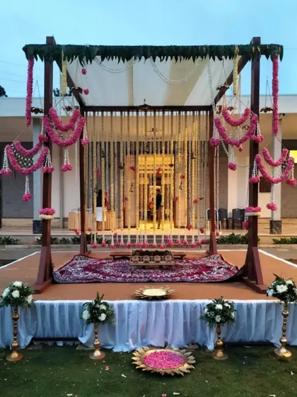 A different angle of the pink and white outdoor mandap, showing the intricate floral hangings and the traditional rug placed for the ceremony, blending modern and classic elements seamlessly.