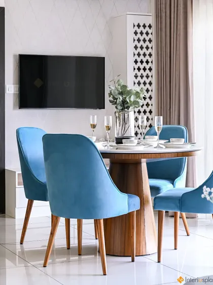 A cozy dining setup with a round wooden table and comfortable blue upholstered chairs. This space is perfect for intimate family meals and conversations.