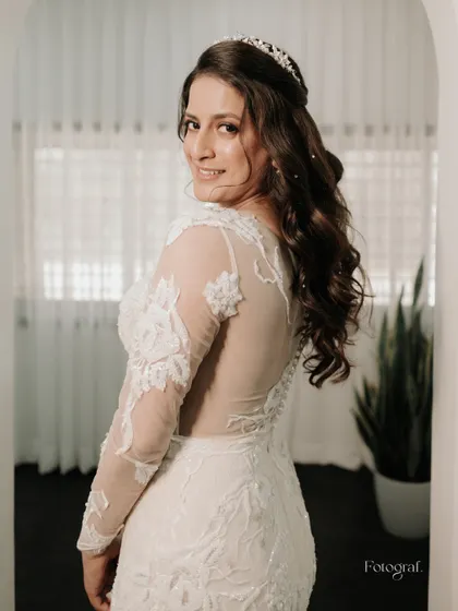 A lovely portrait of the bride looking over her shoulder with a sweet smile, showcasing the beautiful back and sleeve detail of her gown.