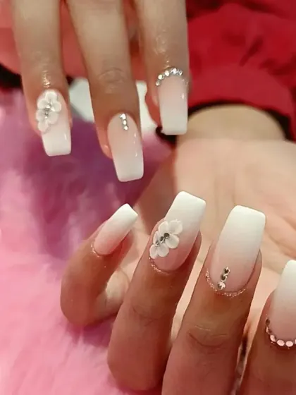 A bridal-ready set of square-tipped ombre nails, featuring delicate 3D flowers and rhinestone accents.