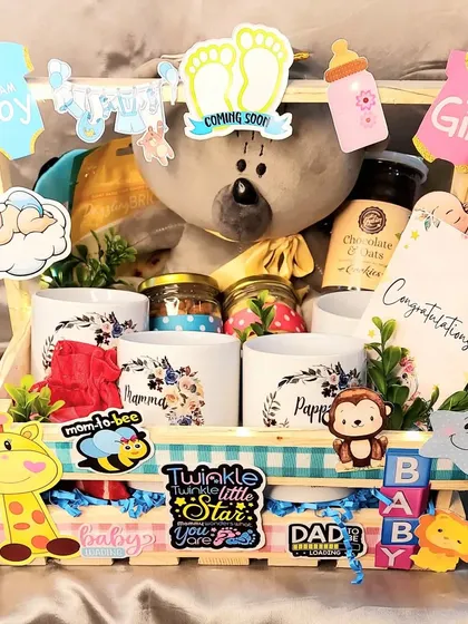 Another take on our popular baby shower hamper. This one is filled with treats, mugs for mom and dad, and a cute grey teddy bear, all decorated with fun baby-themed cutouts.