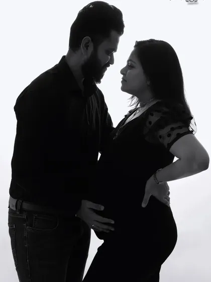 A classic black and white portrait of an expecting couple. This high-key photo creates a timeless and elegant look, focusing on their connection and the silhouette of the pregnancy.