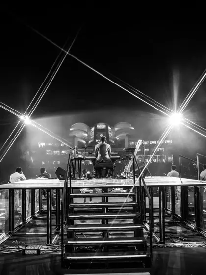 A timeless, black and white shot of the stage from behind the artist's platform. It highlights the intricate structure and lighting design that forms the backbone of our productions.