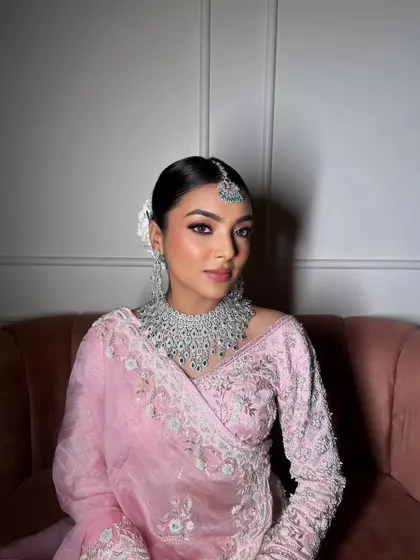 The client looking flawless in pastel pink. The sleek bun and fresh flowers complement her diamond and emerald jewelry perfectly.
