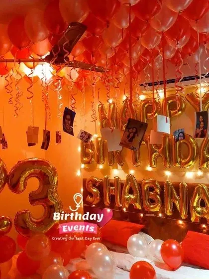 A vibrant red-themed 23rd birthday surprise. This bedroom setup includes large foil numbers, a personalized name banner, and photos hanging from the ceiling.