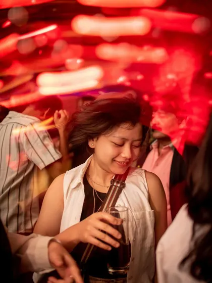 A guest enjoying a drink and the music, bathed in the red light of the club.
