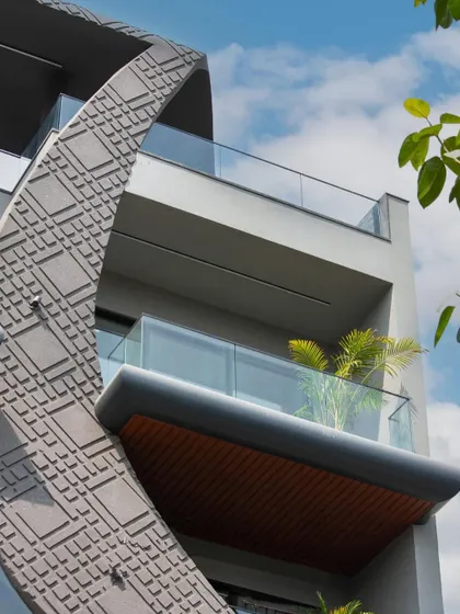 A close-up of the wave-form facade, showing the texture of the concrete grooving and the clean lines of the glass balcony railings. The design is both sculptural and functional.