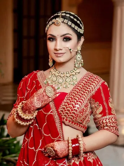 A classic red bridal look for the modern bride. The makeup features defined, kohl-rimmed eyes and a matte red lip, paired with a traditional matha patti for a regal and timeless appearance.
