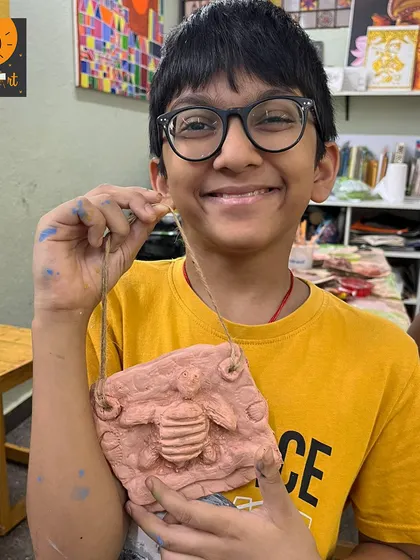 What a happy smile! This student created a wonderful clay mural featuring a bee, using tools to add details and texture to his creation.